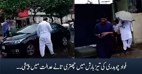 Fawad Chaudhry appears in court holding an umbrella in the rain