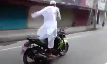 Pakistani Baba Dhoom, An Old Man Driving Motorcycle on Busy Road with His Hands Up
